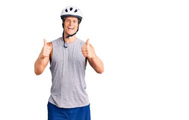 Young handsome man wearing bike helmet success sign doing positive gesture with hand, thumbs up smiling and happy. cheerful expression and winner gesture.