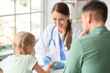 Doctor measuring blood sugar level of little girl in clinic
