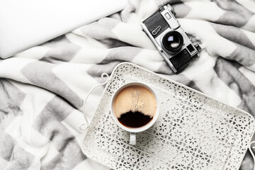 Tray with cup of coffee and photo camera on plaid