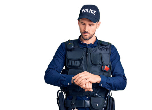 Young handsome man wearing police uniform checking the time on wrist watch, relaxed and confident
