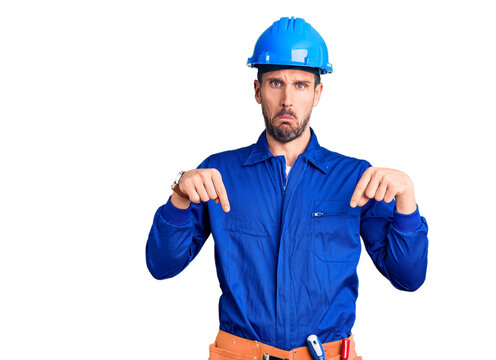 Young handsome man wearing worker uniform and hardhat depressed and worry for distress, crying angry and afraid. sad expression.