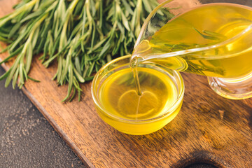 Pouring of rosemary oil from gravy boat into bowl, closeup