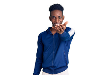 Young african american man wearing sportswear smiling friendly offering handshake as greeting and welcoming. successful business.