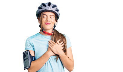 Beautiful caucasian young woman wearing bike helmet smiling with hands on chest with closed eyes and grateful gesture on face. health concept.