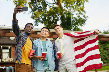 Low angle portrait of multi-ethnic group of taking selfie while enjoying outdoor party in Summer for Independence day