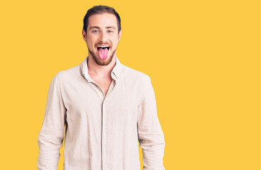 Young handsome caucasian man wearing casual clothes sticking tongue out happy with funny expression. emotion concept.