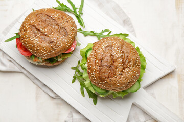 Board with tasty vegan burgers on table
