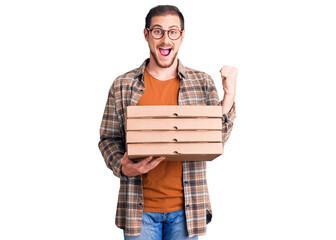 Young handsome caucasian man holding delivery pizza box screaming proud, celebrating victory and...