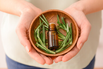 Woman with bottle of rosemary oil, closeup