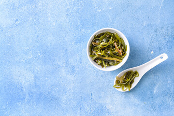 Bowl with tasty seaweed on color background