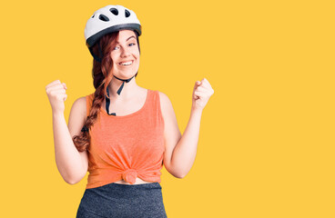 Young beautiful woman wearing bike helmet screaming proud, celebrating victory and success very excited with raised arms