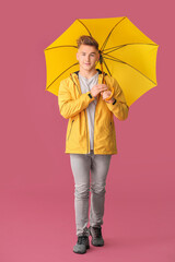 Young man with umbrella on color background