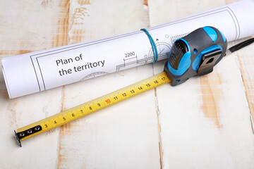 Measuring tape with blueprint on wooden background