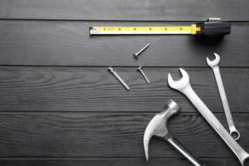 Measuring tape with builder's supplies on wooden background