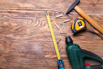 Measuring tape with builder's supplies on wooden background
