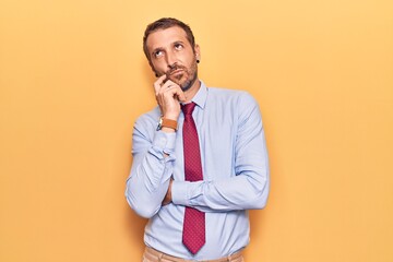 Young handsome man wearing business clothes serious face thinking about question with hand on chin,...