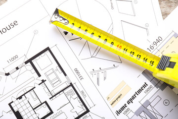 Measuring tape with blueprints on table