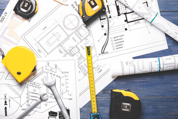 Measuring tapes with builder's supplies and blueprint on table