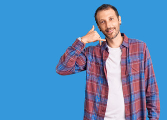 Young handsome man wearing casual clothes smiling doing phone gesture with hand and fingers like talking on the telephone. communicating concepts.