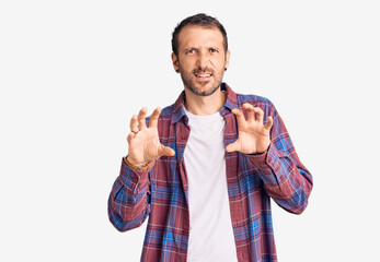Young handsome man wearing casual clothes smiling funny doing claw gesture as cat, aggressive and...