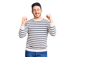 Fototapeta premium Young hispanic man wearing casual clothes excited for success with arms raised and eyes closed celebrating victory smiling. winner concept.