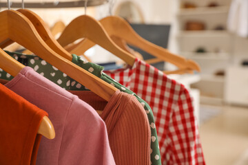 Hanger with stylish clothes in modern store, closeup