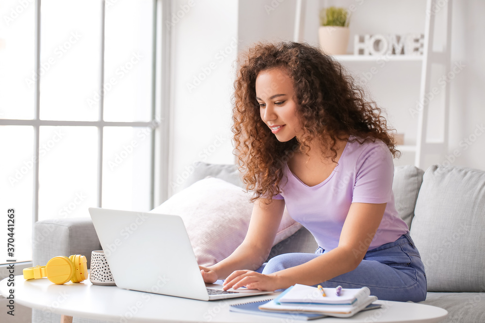 Wall mural Young woman using laptop for online learning at home