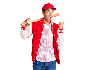Young african amercian man playing baseball holding bat and ball pointing thumb up to the side smiling happy with open mouth