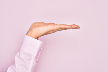 Hand of caucasian young man showing fingers over isolated pink background with flat palm presenting product, offer and giving gesture, blank copy space