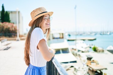 Fototapeta premium Young blonde woman on vacation smiling happy leaning on balustrade at street of city