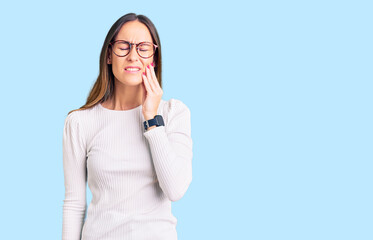 Fototapeta premium Beautiful brunette young woman wearing casual white sweater and glasses touching mouth with hand with painful expression because of toothache or dental illness on teeth. dentist