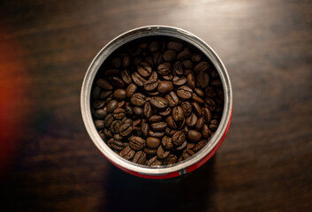 Fototapeta premium brown roasted coffee beans in a recipient on a wooden table