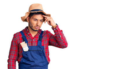 Handsome latin american young man weaing handyman uniform worried and stressed about a problem with hand on forehead, nervous and anxious for crisis