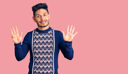 Naklejka premium Handsome latin american young man wearing casual winter sweater showing and pointing up with fingers number eight while smiling confident and happy.