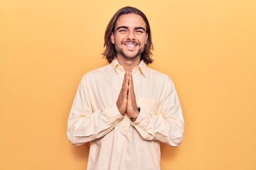 Young handsome man wearing business clothes praying with hands together asking for forgiveness smiling confident.