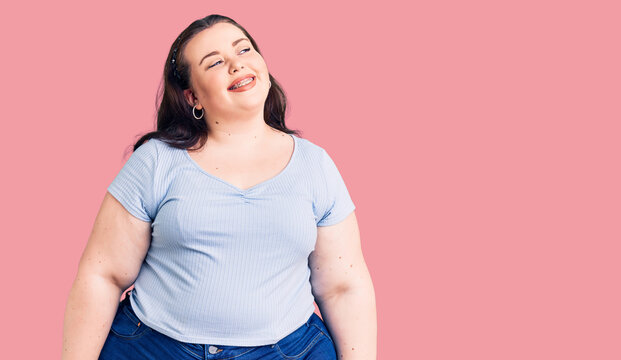 Young plus size woman wearing casual clothes looking away to side with smile on face, natural expression. laughing confident.