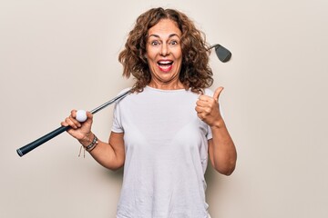 Middle age beautiful sportswoman playing golf using stick and ball over white background pointing thumb up to the side smiling happy with open mouth
