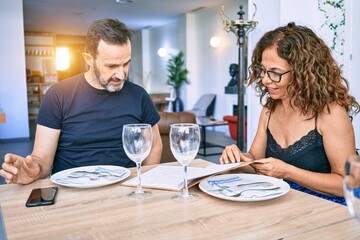 Middle age beautiful couple wearing casual clothes smiling happy. Sitting with smile on face reading restaurant menu.
