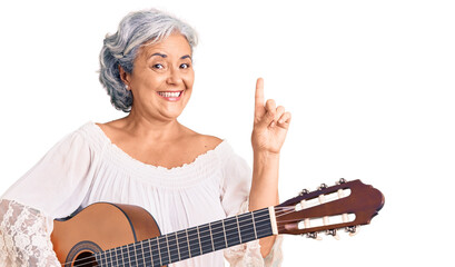 Fototapeta premium Senior woman with gray hair playing classical guitar surprised with an idea or question pointing finger with happy face, number one