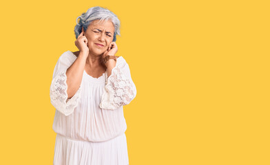 Senior woman with gray hair wearing bohemian style covering ears with fingers with annoyed expression for the noise of loud music. deaf concept.
