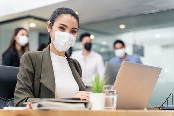 Asian young businesswoman wearing mask working on computer in office. - Powered by Adobe