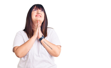 Young plus size woman wearing casual clothes begging and praying with hands together with hope expression on face very emotional and worried. begging.