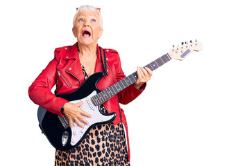 Senior beautiful woman with blue eyes and grey hair wearing a modern look playing electric guitar angry and mad screaming frustrated and furious, shouting with anger. rage and aggressive concept.
