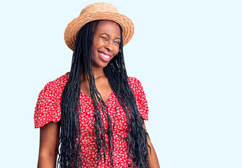 Young african american woman wearing summer hat winking looking at the camera with sexy expression,...