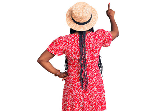 Young african american woman wearing summer hat posing backwards pointing ahead with finger hand