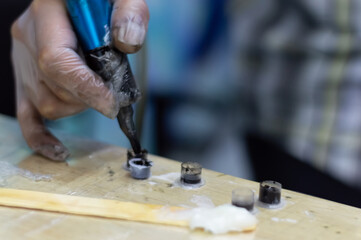 Tattoo artist holding a tattoo machine and dip into inks for tattooing