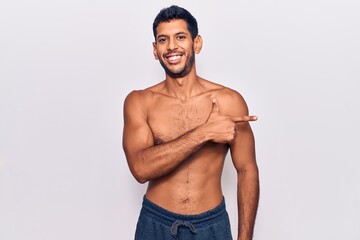 Fototapeta na wymiar Young latin man standing shirtless cheerful with a smile of face pointing with hand and finger up to the side with happy and natural expression on face