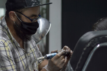 Closeup shot tattoo artist holding a tattoo machine tattooing a person
