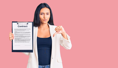 Young beautiful latin girl holding clipboard with contract document with angry face, negative sign...