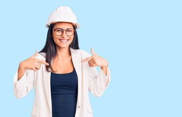Young beautiful latin girl wearing architect hardhat and glasses looking confident with smile on...